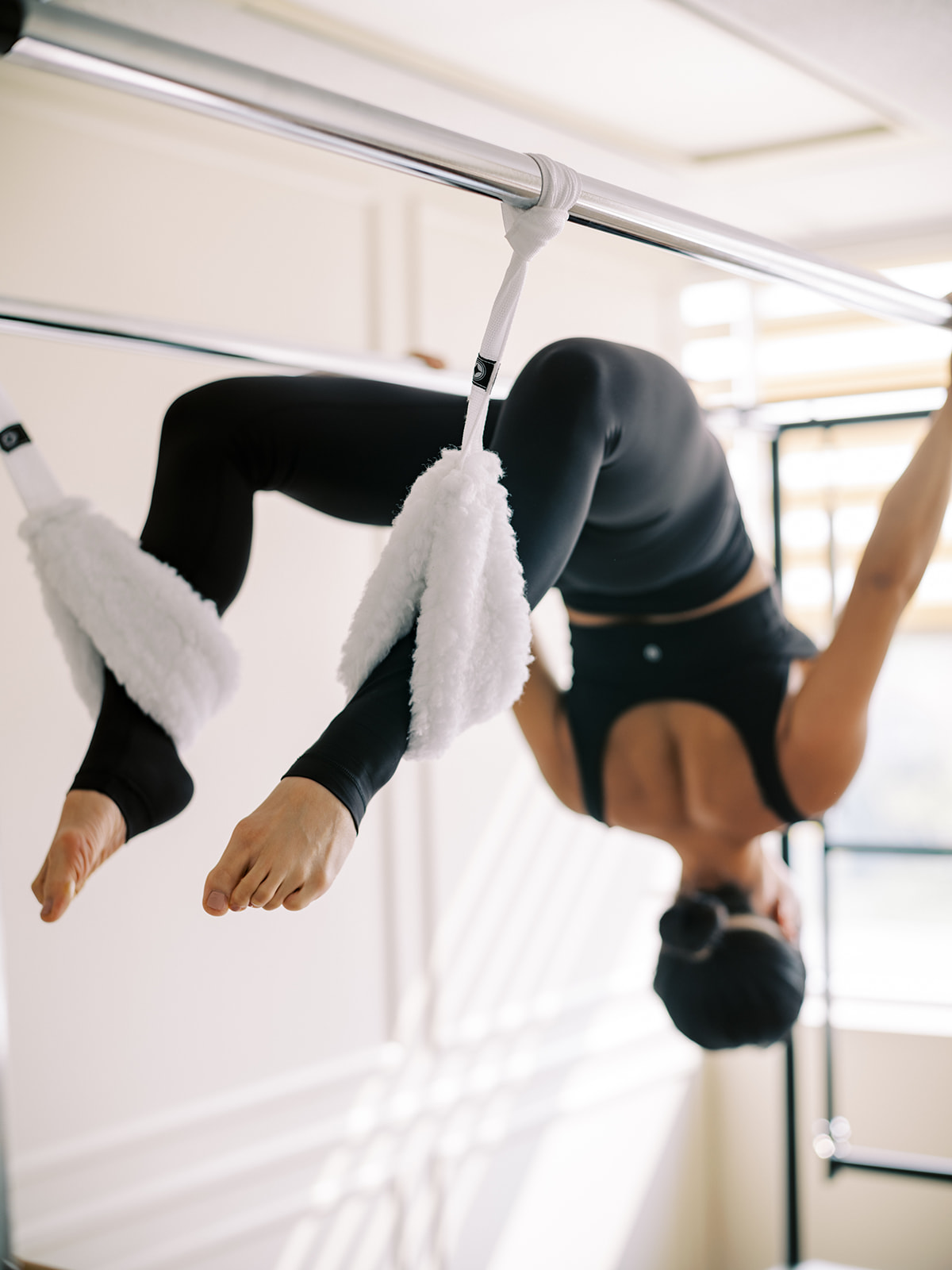 Client practicing an inverted Cadillac exercise in the Mi Pilates studio